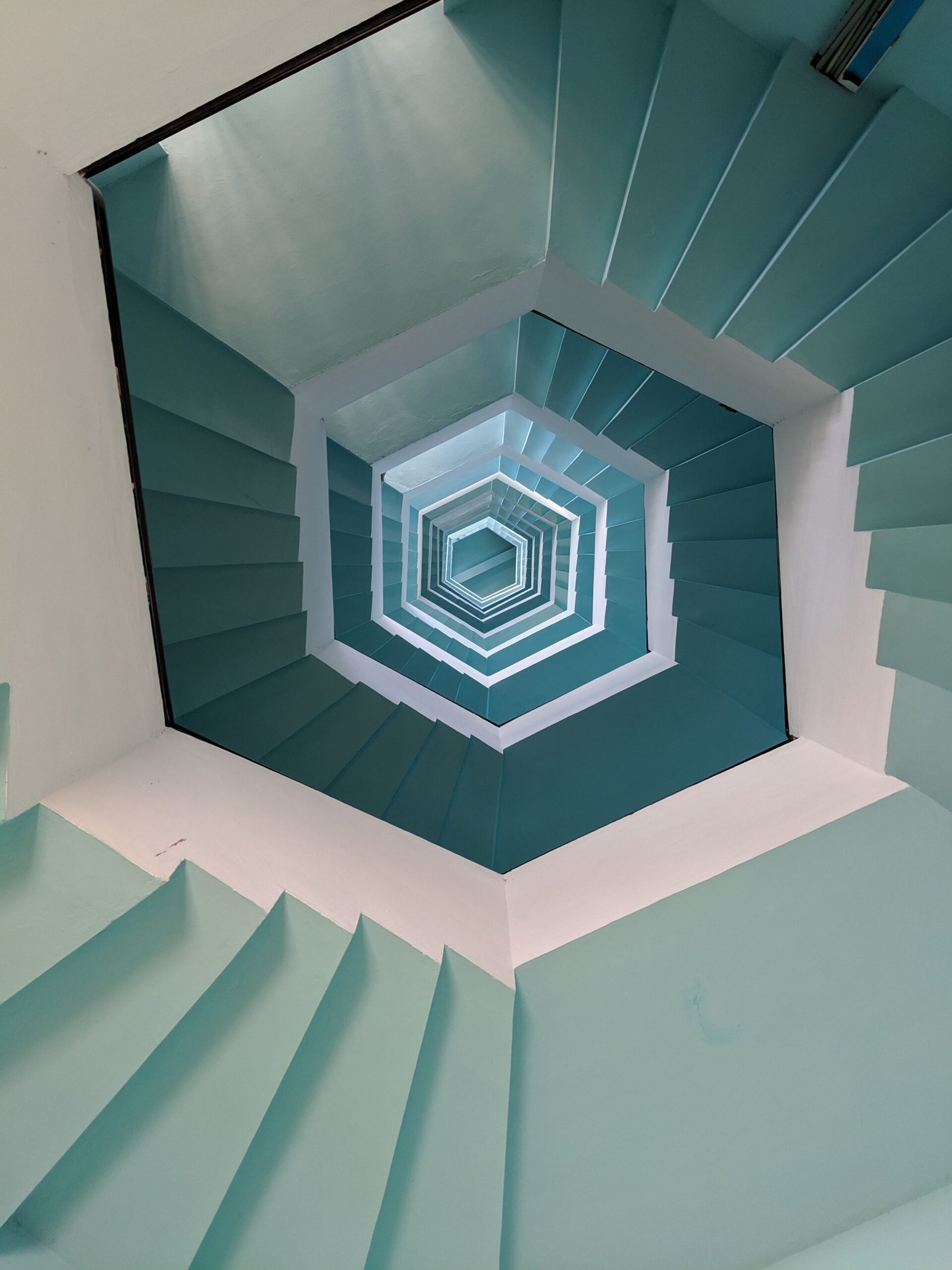 Vertical view of a geometric stairwell with a blue pattern in Puducherry, India.